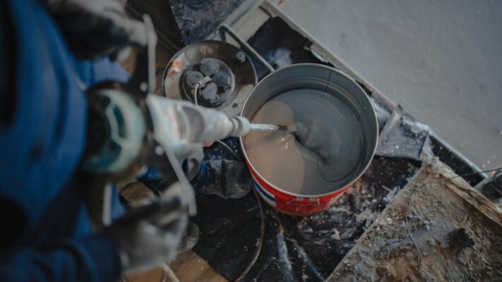 a person mixing damp proofing in a bucket